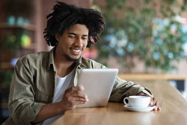 Jovem afro-americano cara relaxante com Digital Tablet e café no café — Fotografia de Stock