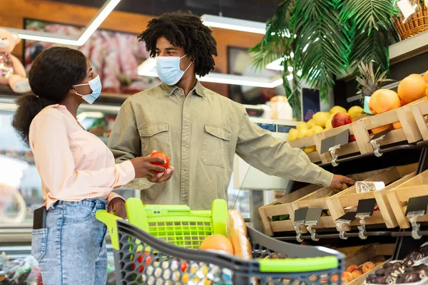 Casal de família negra fazendo compras de supermercado vestindo máscaras no supermercado — Fotografia de Stock