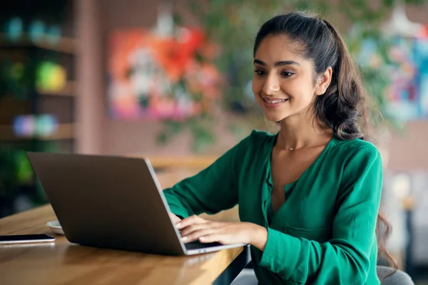 カフェでオンラインで勉強するかなりインド人女性,ラップトップを使用して,空のスペース — ストック写真