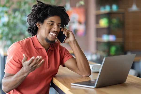 Telecomando. nero ragazzo utilizzando computer portatile e parlando su cellulare in caffè — Foto Stock