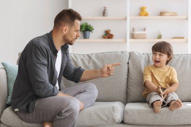 Aile içi şiddet ve çocuk istismarı. Öfkeli baba küçük oğluna kızmalı, ağlayan çocuk gücenmiş hissediyor.
