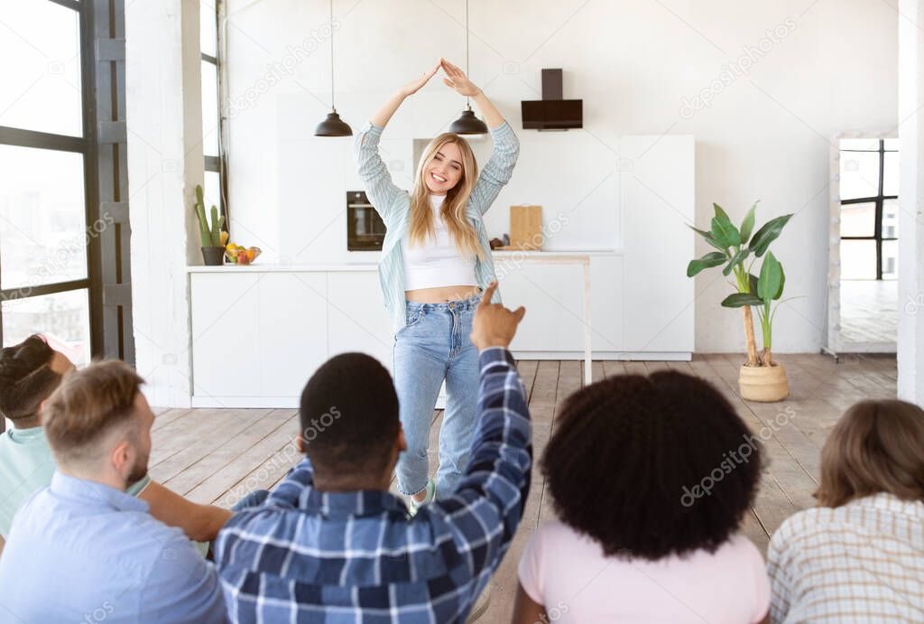 Group of millennial diverse friends playing charades at home