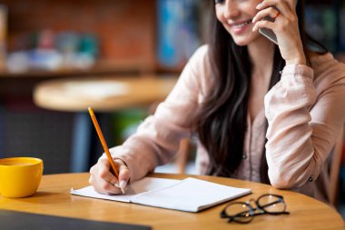 Jop fırsatı arıyorum. Akıllı telefondan konuşan, notlar alan, kafenin içinde oturan genç bir kadın.