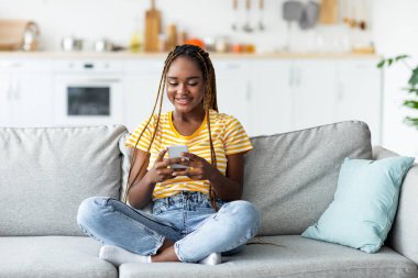 Evde cep telefonu kullanan tatlı Afro-Amerikalı kadın.