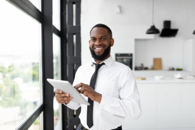 Kameraya bakarak dijital tablet kullanan Afrikalı Amerikalı bir adam.