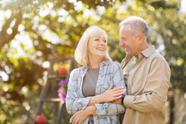 Emekli eşleri sevmek parkta birlikte vakit geçirmek güneşli bir sonbahar gününde yürümek, karısını kucaklayan bir adam, boş bir alan.