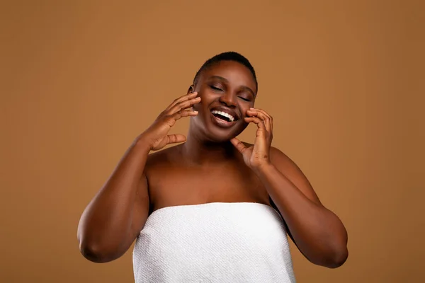 Beautiful young african american woman applying face moisturizer — Stock Photo, Image