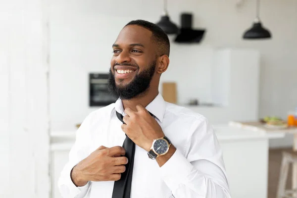 Lächelnder afroamerikanischer Geschäftsmann beim Anpassen der Krawatte — Stockfoto