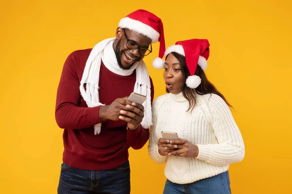 African Man Visar Smartphone till flickvän Rekommendera ansökan, Gul bakgrund — Stockfoto