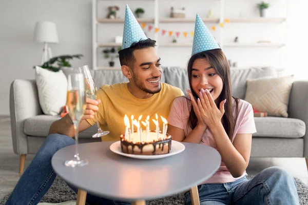 Cool arabisk kille gör födelsedagsöverraskning för sin upphetsade flickvän, presenterar födelsedagstårta, dricker champagne hemma — Stockfoto