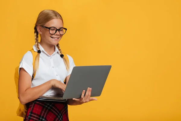 Veselý inteligentní běloška mladá dívka student v brýlích studium s notebookem, izolované na žlutém pozadí — Stock fotografie