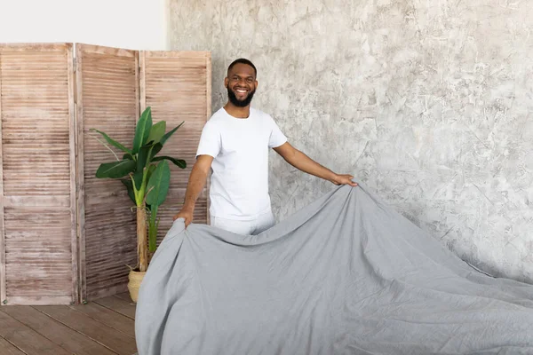 Satisfecho joven afroamericano hombre haciendo cama —  Fotos de Stock