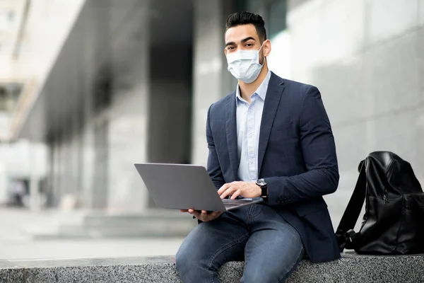 Árabe cara empreendedor sentado na rua, usando laptop — Fotografia de Stock