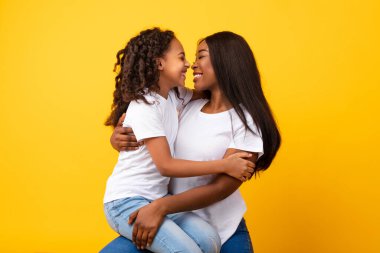 African American woman hugging her smiling daughter at studio clipart