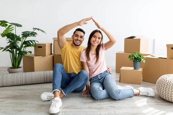 Арабський чоловік і його дівчина роблять жести, сидячи на підлозі серед коробки з-під картону, переїжджаючи до нового дому. — стокове фото