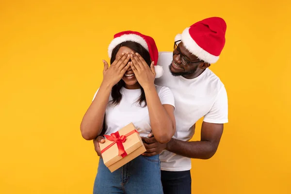 African American Guy Överraskande flickvän med julklapp, gul bakgrund — Stockfoto
