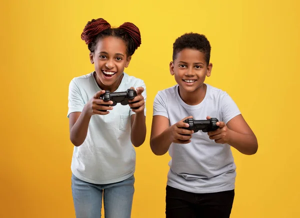 Alegre preto irmão e irmã segurando joysticks — Fotografia de Stock