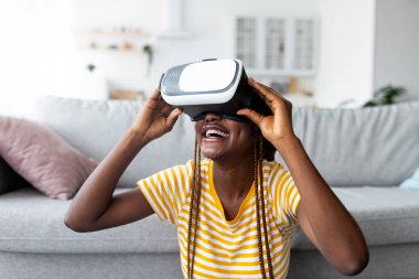 Bin yıllık siyahi kadının evde VR gözlüğü kullanması.