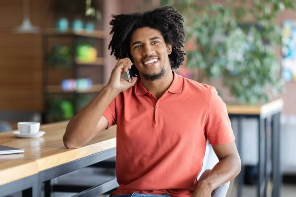 Mobilfunk. Glücklich junger schwarzer Mann im Gespräch auf Handy im Cafe — Stockfoto