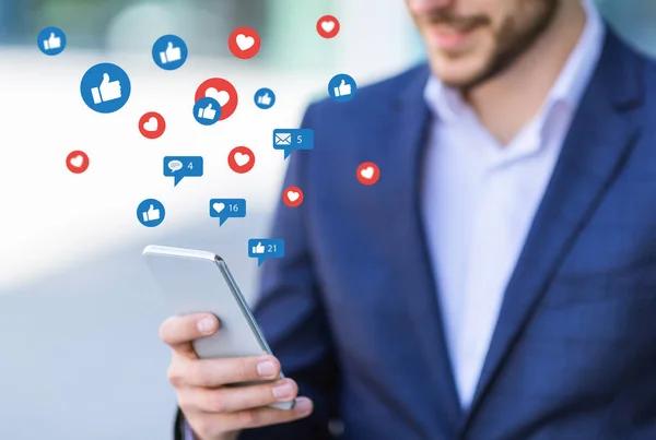 Sonriente millennial hombre de negocios en traje charlando por teléfono en las redes sociales, al aire libre — Foto de Stock