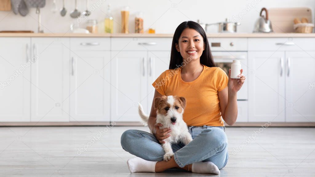 Cheerful asian lady with cute doggy showing pets supplement jar