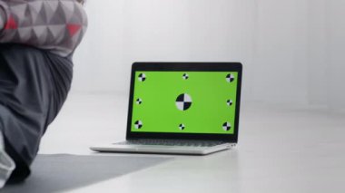 Spor spikeri evde çalışıyor, dizüstü bilgisayarda video dersi izliyor, takip işaretli yeşil renkli ekran