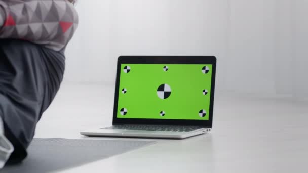 Sportman thuis aan het trainen, video-tutorial bekijken op laptop, groen chroma sleutelscherm met tracking markers — Stockvideo