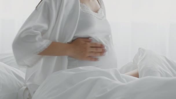 Onherkenbare zwangere dame aanraken buik tijdens het zitten in bed, lijden prenatale weeën — Stockvideo