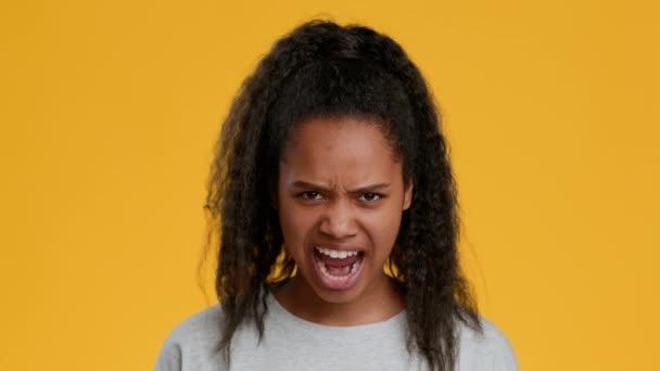 Enojado negro adolescente chica gritando posando sobre amarillo fondo — Vídeos de Stock