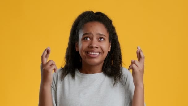 Anxieux noir adolescent fille garder doigts croisés sur jaune fond — Video