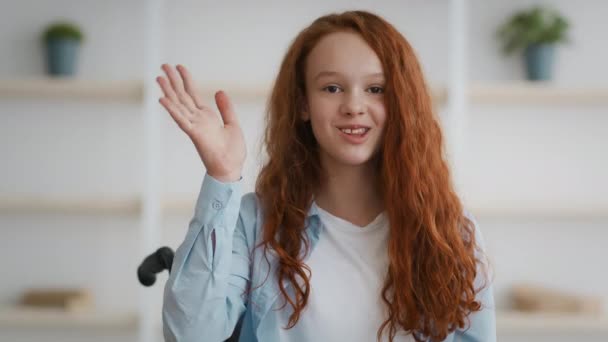 Deficiência e positivo. Menina ruiva bonito pouco deficiente em cadeira de rodas e acenando mão para câmera, dizendo olá para — Vídeo de Stock