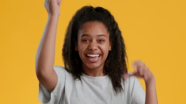 Radostné africké dospívající dívka gesturing ano slavit úspěch, žluté pozadí — Stock video