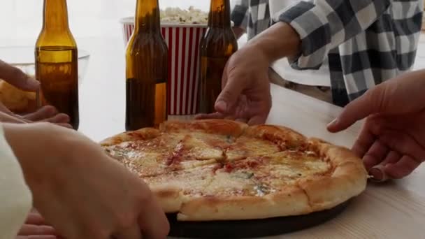 Группа друзей, принимающих ломтики пиццы из деревянной тарелки на домашней вечеринке — стоковое видео