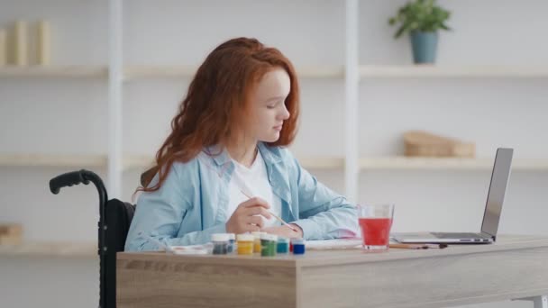 Kunstterapi for handicappede børn. Lille handicappet pige tegning derhjemme, ser online tutorial på laptop, slow motion – Stock-video