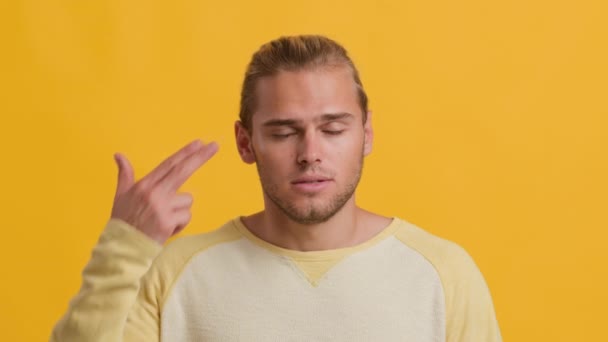 Uttråkad ung stilig kille gör självmord Gesture med fingrar nära templet — Stockvideo