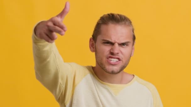 Aggressive Young Guy Shooting At Camera With Finger Gun Over Yellow Background — Stok Video