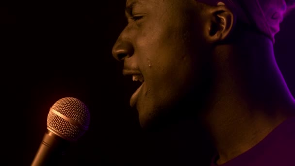 Känslomässig svart sångerska Guy sjunga nära mikrofon i mörk studio — Stockvideo