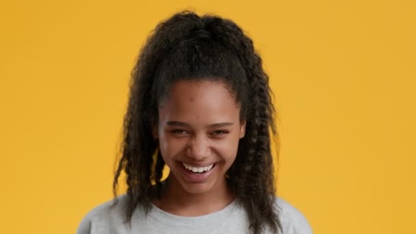 Afrikansk amerikansk tonåring flicka skratta ut högt över gul bakgrund — Stockvideo