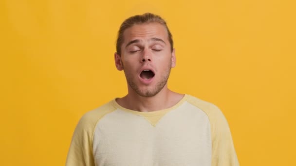 Porträtt av trött kille Yawning, Täcka munnen med handen över gul bakgrund — Stockvideo