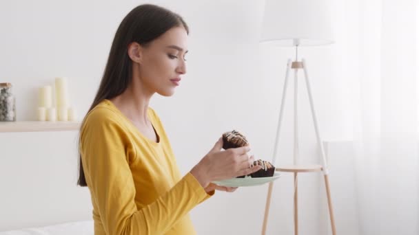 Graviditet illamående. Ung gravid dam vill äta muffins hemma, lukta på den och springa till badrummet med kräkningar — Stockvideo
