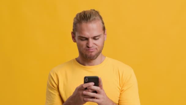 Conectados Namoro App. Jovem descontente usando Smartphone sobre fundo amarelo, — Vídeo de Stock