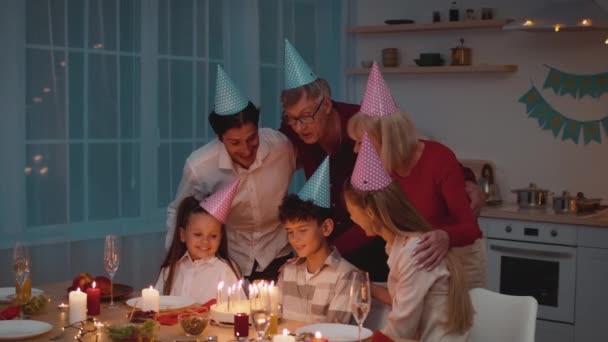 Familia celebrando hijos cumpleaños soplando velas en la torta en casa — Vídeo de stock