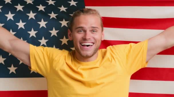 Felice giovane patriottico che si tiene e si avvolge nella bandiera degli Stati Uniti — Video Stock