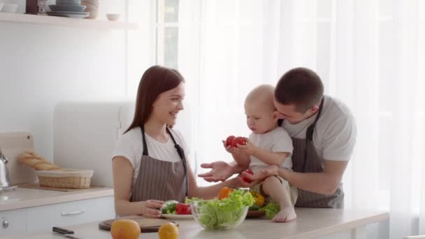 Junge liebevolle Eltern kochen mit ihrem süßen kleinen Baby in der Küche — Stockvideo