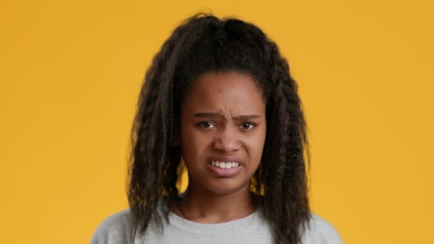 Disgustada adolescente africana frunciendo el ceño y sacudiendo la cabeza, fondo amarillo — Vídeos de Stock