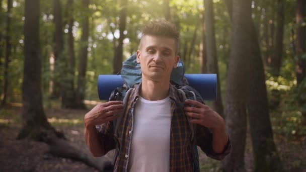 Joven mochilero con equipo turístico sonriendo a la cámara, posando a la cámara, de pie en el bosque de otoño — Vídeo de stock