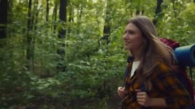 Genç, mutlu, aktif bayan sırt çantalı, güz ağacında yürüyor, doğanın tadını çıkarıyor, sırtında ekipmanla sırt çantası taşıyor.