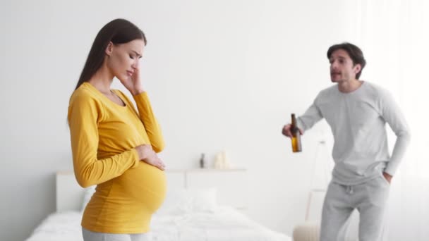 집에서 술취한 남편때문에 고통받는 임신 한 젊은 여자, 성난 남자 맥주 병으로 아내에게 소리치는 남자 — 비디오