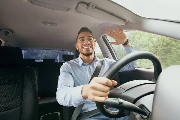 Allegro ragazzo del Medio Oriente che guida auto, salutando qualcuno — Foto Stock
