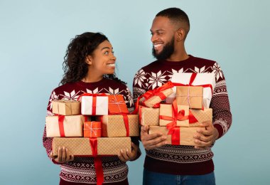 Siyahi eşleri sevmek Noel hediyesi kutuları taşımak ve birbirlerine gülümsemek. Yeni yılı kutlamaya hazırlar.